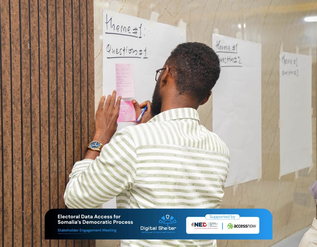 A participant placing a sticky note on a board labelled with a discussion theme